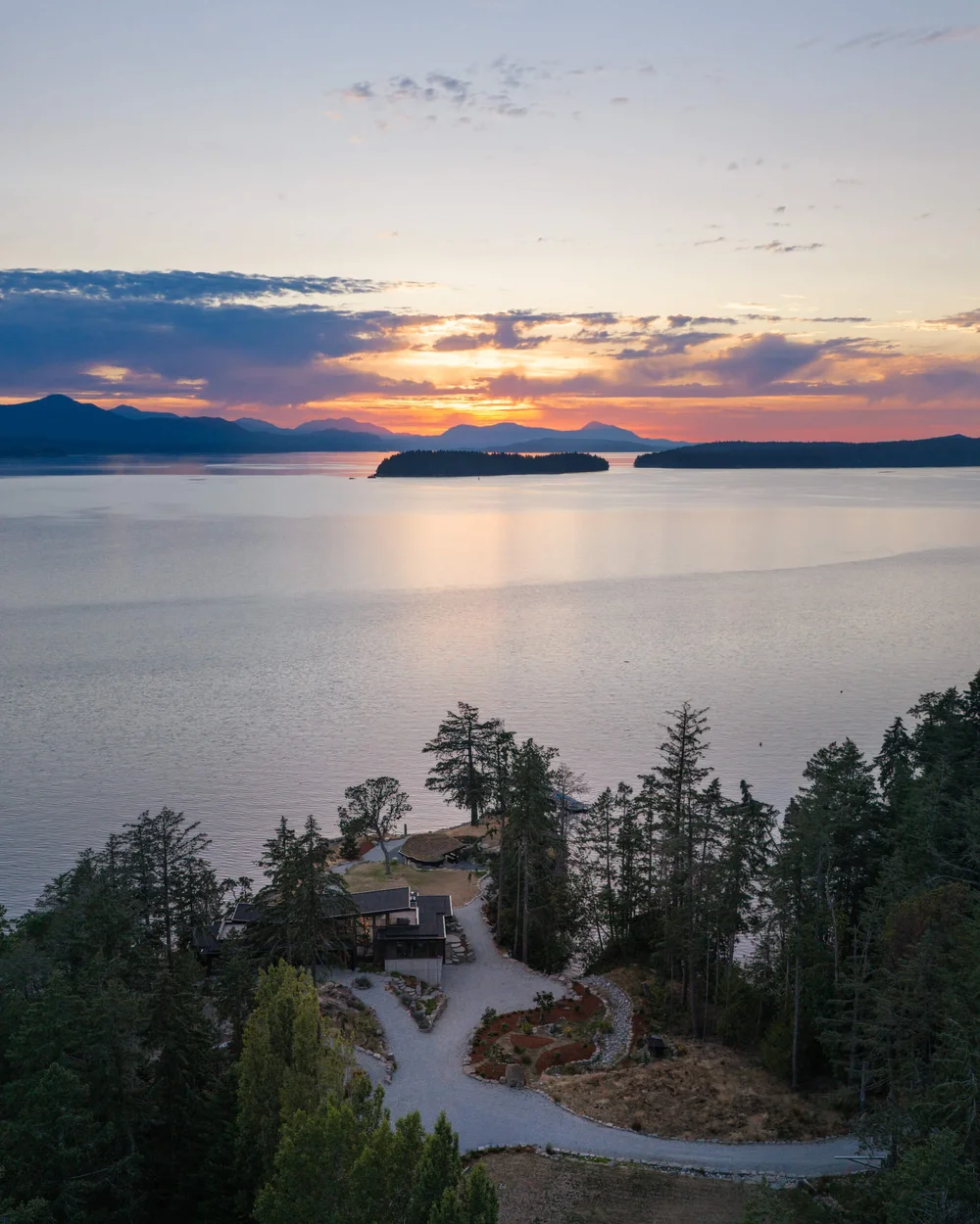 Aerial at sunset over the water, the house on its point in the trees below