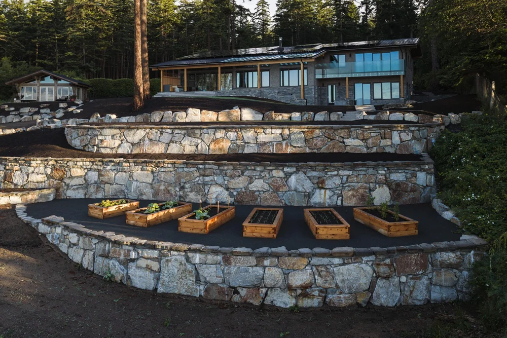 Terraced stone walls stepping down the slope, raised planting beds on the lower level