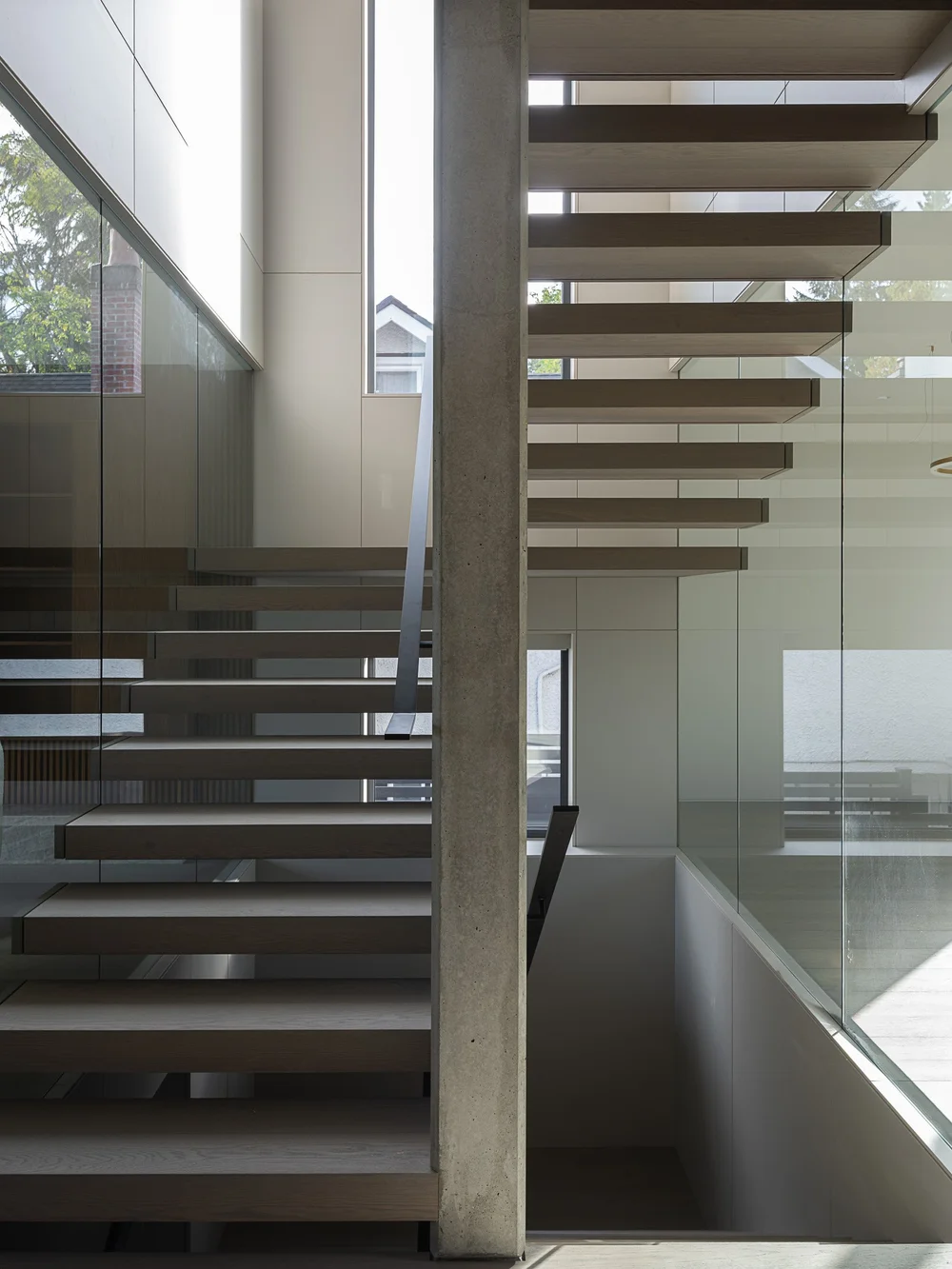 Treads and stringer from below, the concrete wall and glass balustrade above
