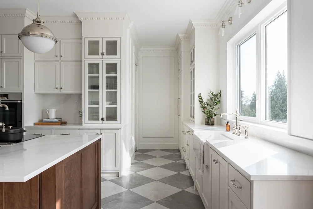 Looking down the kitchen to an apron sink set under a window onto the trees
