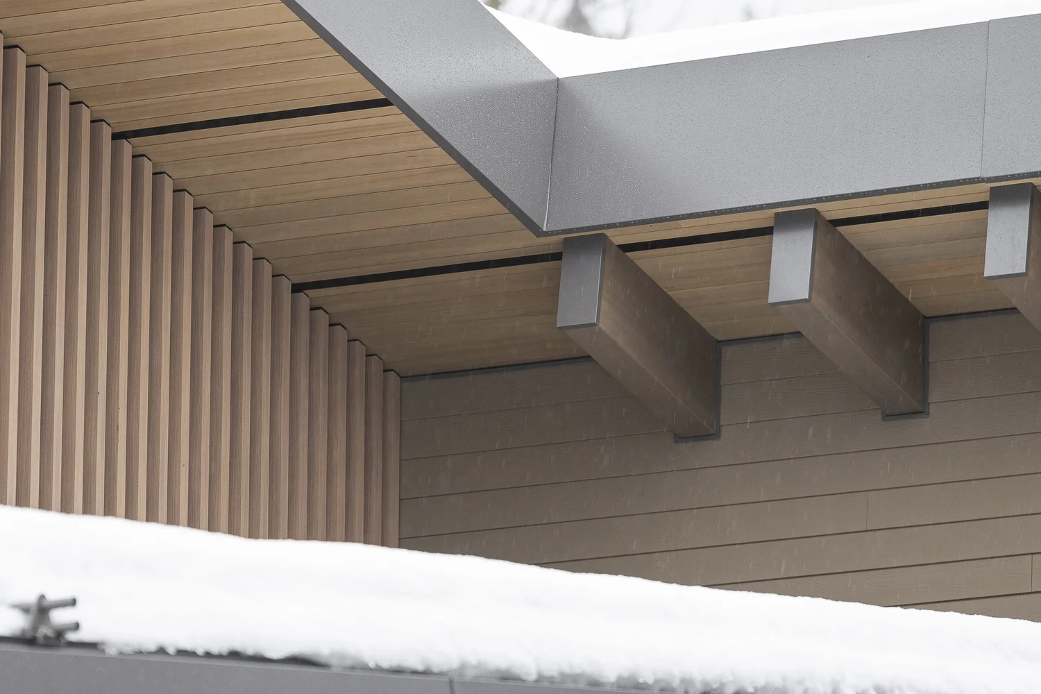 Underside of a deep overhang, vertical fins and beam tails above a bank of snow