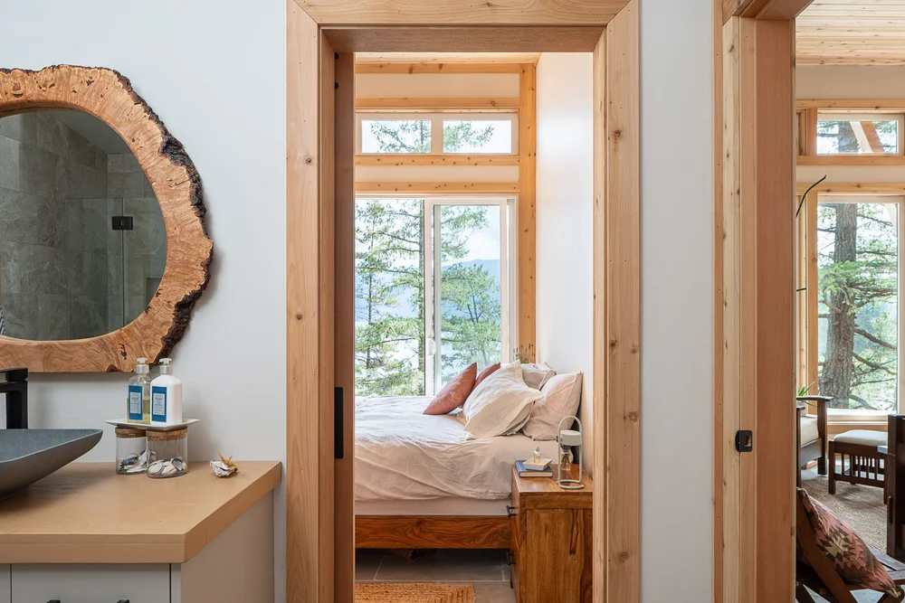 The vanity looking through an open doorway to a bed and windows onto the trees