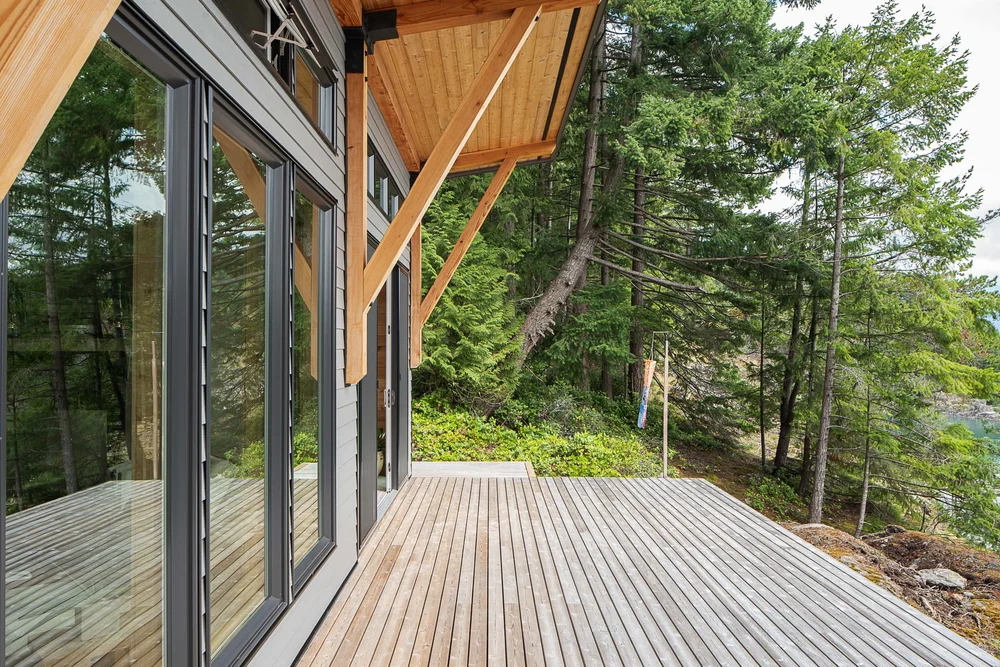 Deck under a wood soffit, sliding glass along the wall and forest beyond the edge