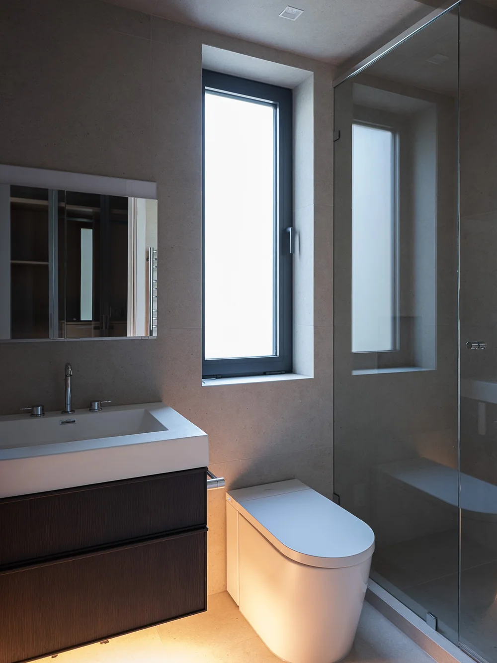 Bathroom vanity and mirror beside a tall window, a glazed shower to the right