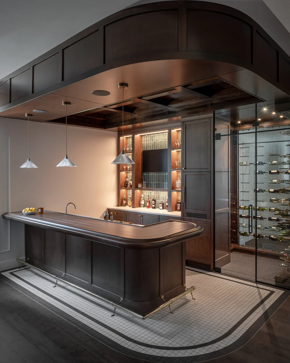 Panelled bar under an arched dark ceiling, lit bottles behind and a glazed wine room