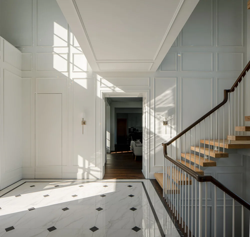 Upper hall with panelled walls and window light across the floor, the stair descending at right