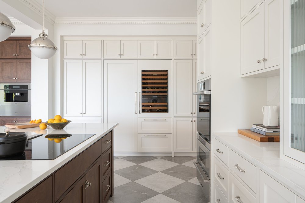 Cream cabinetry with a wine fridge and wall ovens facing the island cooktop