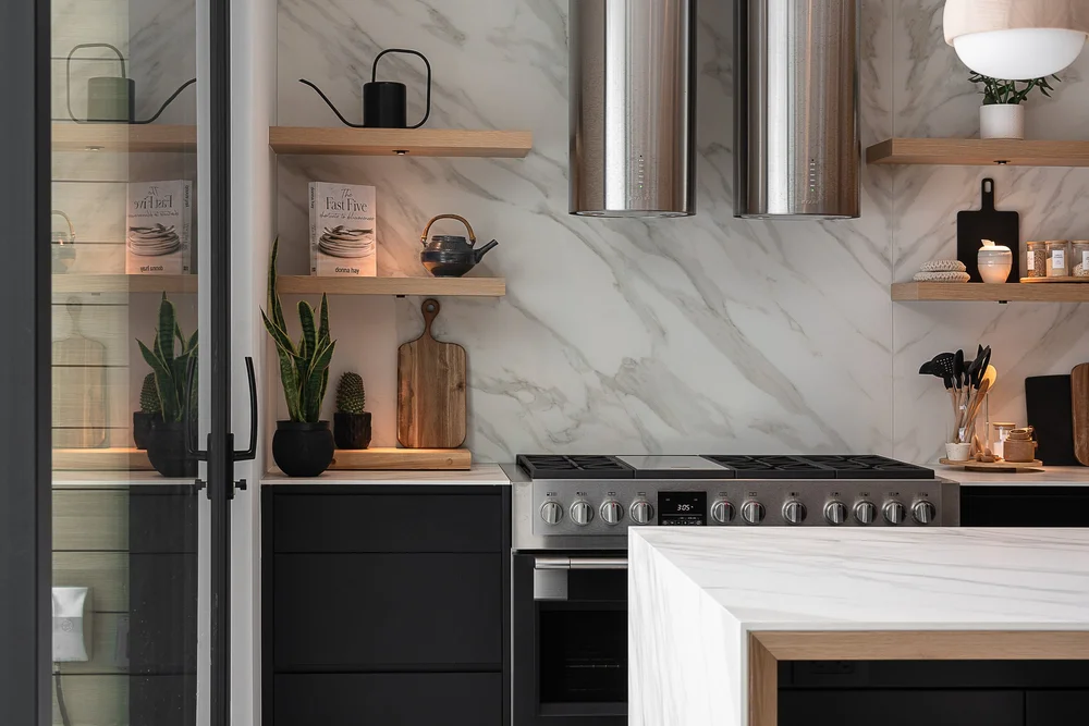 Range and hood against a veined stone backsplash, timber shelves and dark cabinetry