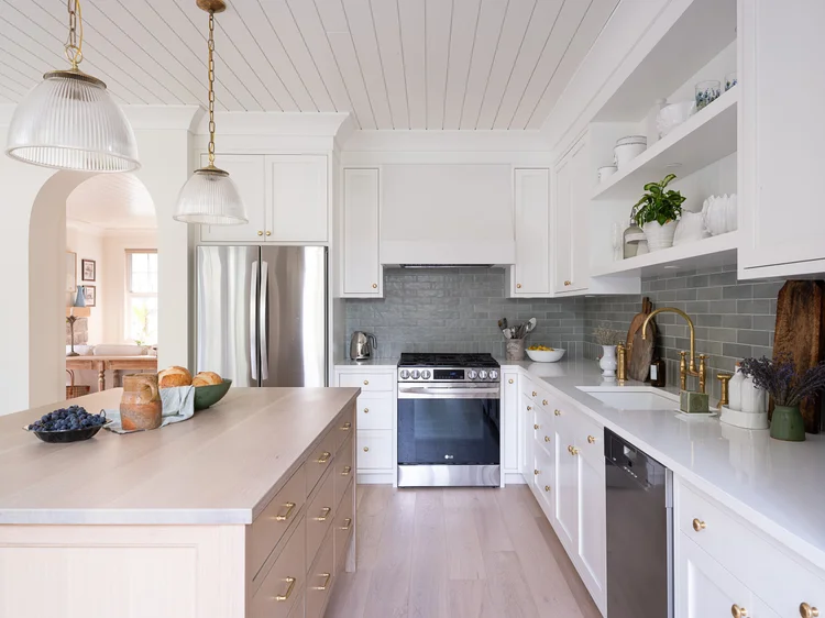 Kitchen under a plank ceiling, ribbed glass pendants over a pale wood island, green tiled wall behind