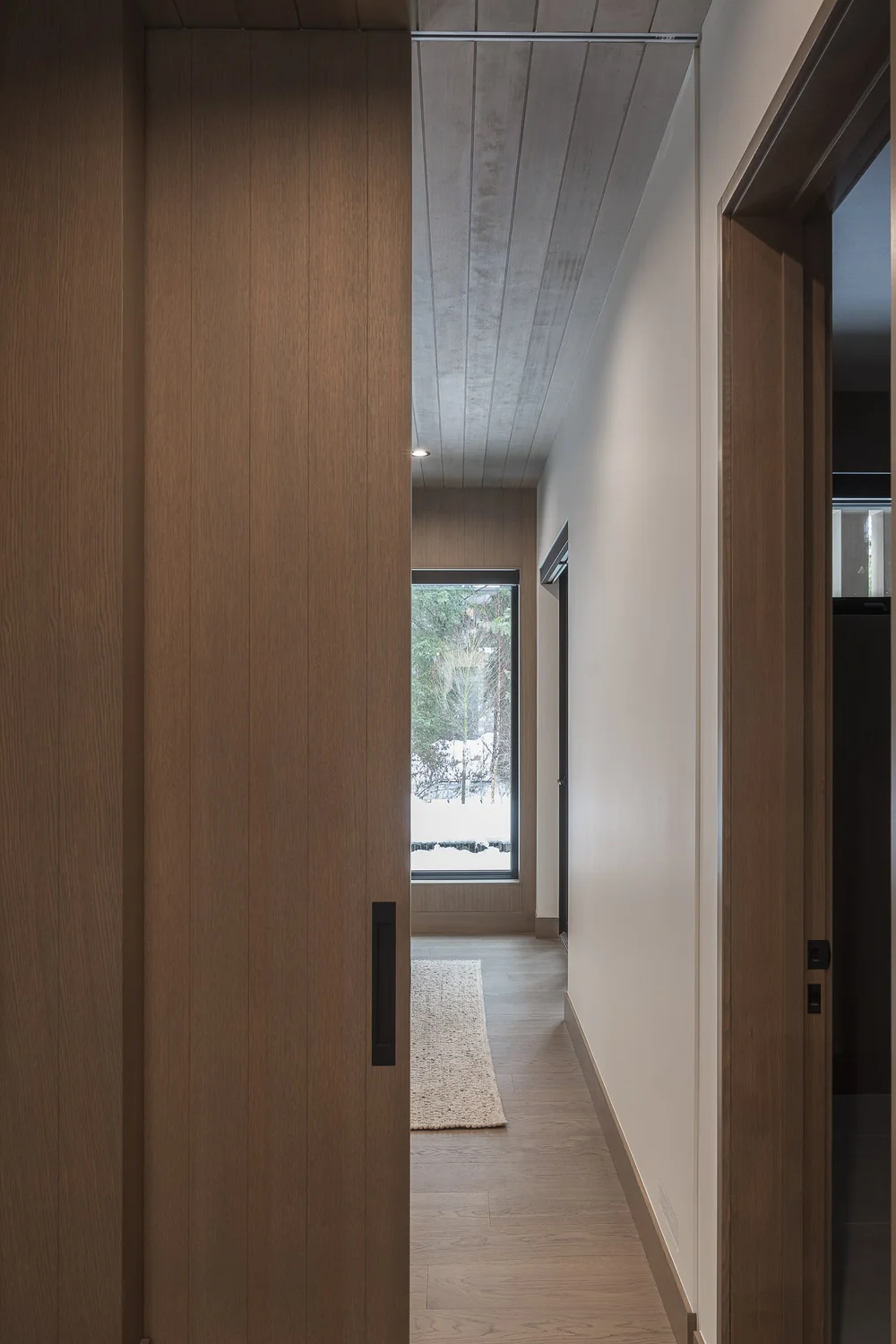Panelled wall with a flush door beside a corridor running away to a window