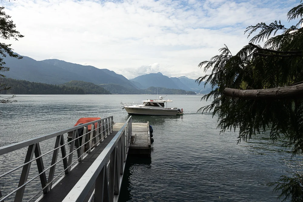 A ramp down to a float with a moored boat, mountains across the channel