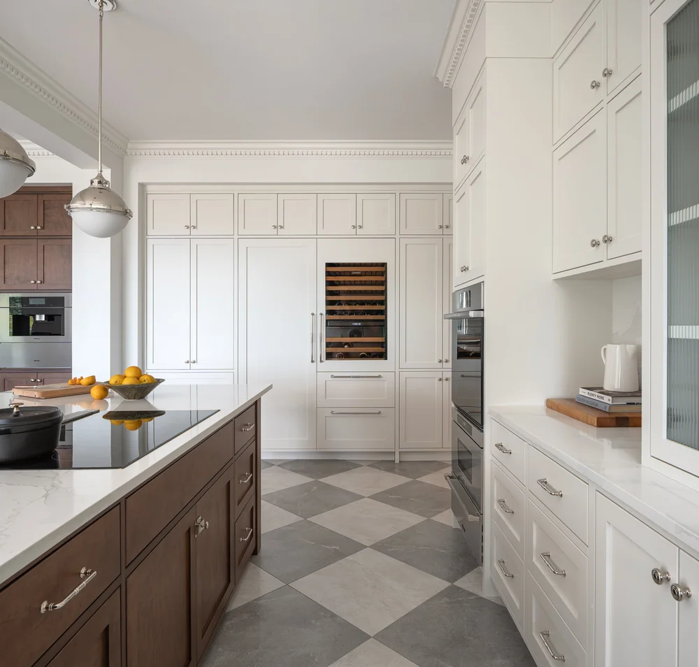 The island cooktop in the foreground, tall cabinetry and a wine fridge along the far wall