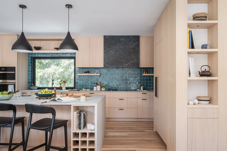 Kitchen island and pale wood cabinetry, tall open shelving at the end of the run