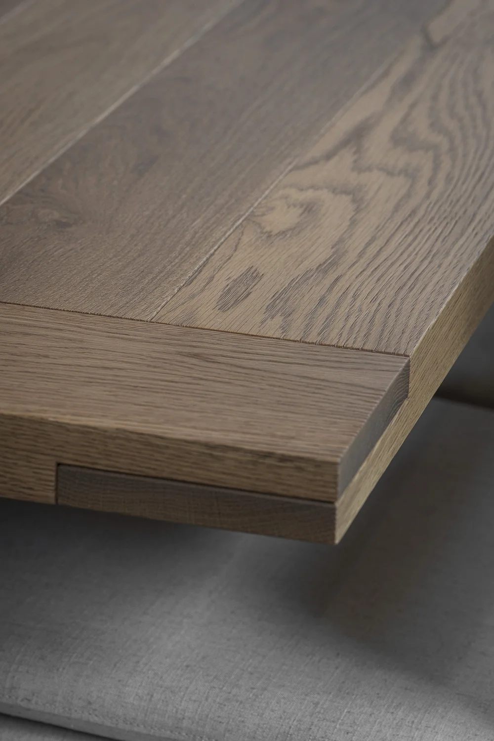 Mitred timber edge stepping over grey fabric below, held in soft focus