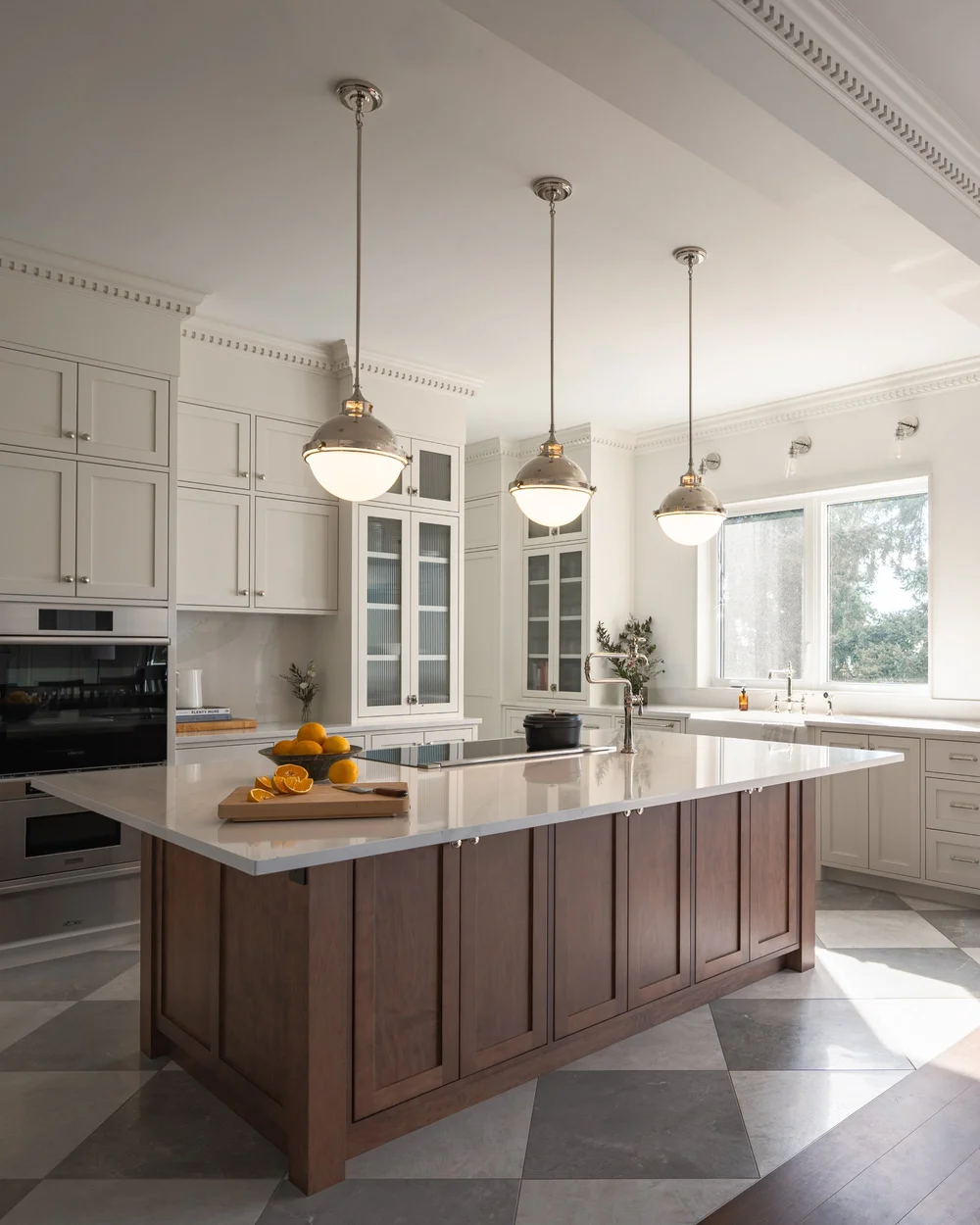 Kitchen from the range end, pendants in a row above the island and a bowl of lemons