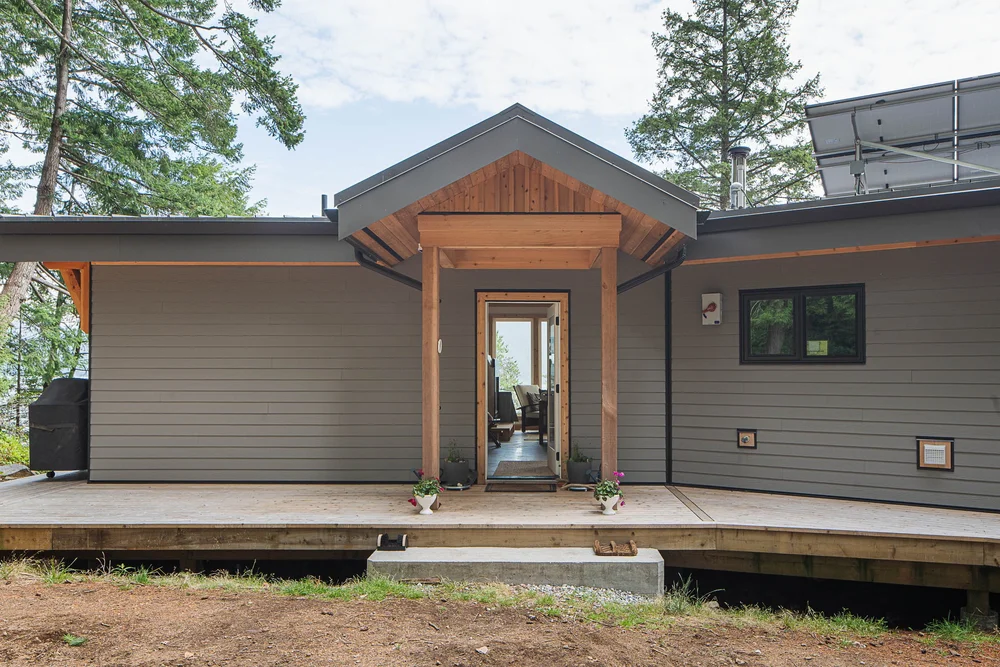 Entry elevation with a gabled porch on wood posts, the door open to the interior