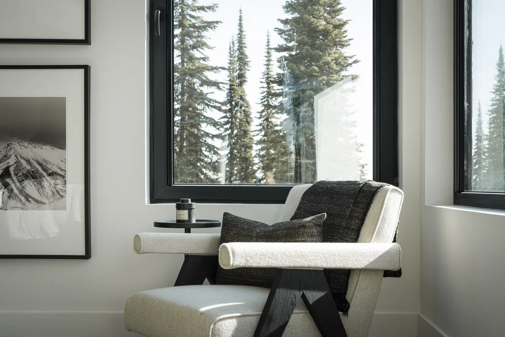 Armchair and ottoman at a corner window, framed print on the wall behind