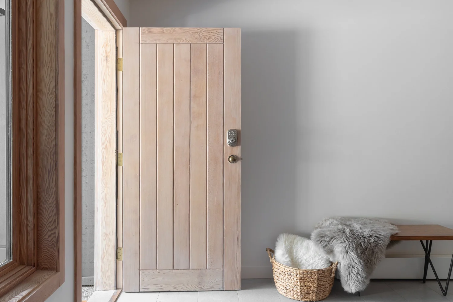 Entry door standing open onto the walk, a sheepskin over a basket beside a bench