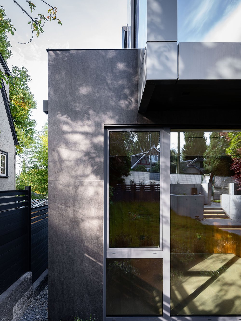 The side elevation, a dark clad pier under the cantilevered upper floor