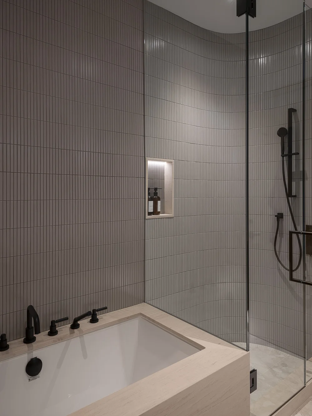 Tub beside a glass shower, ribbed tile running the full height of the wall