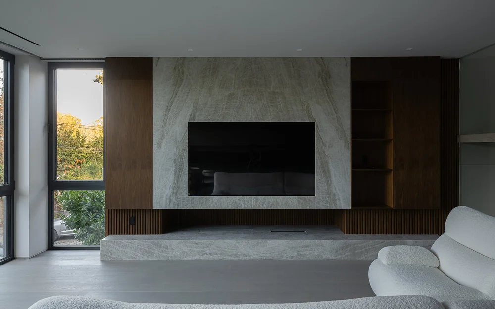 The fireplace wall in stone with a screen above, timber shelving and a raised hearth