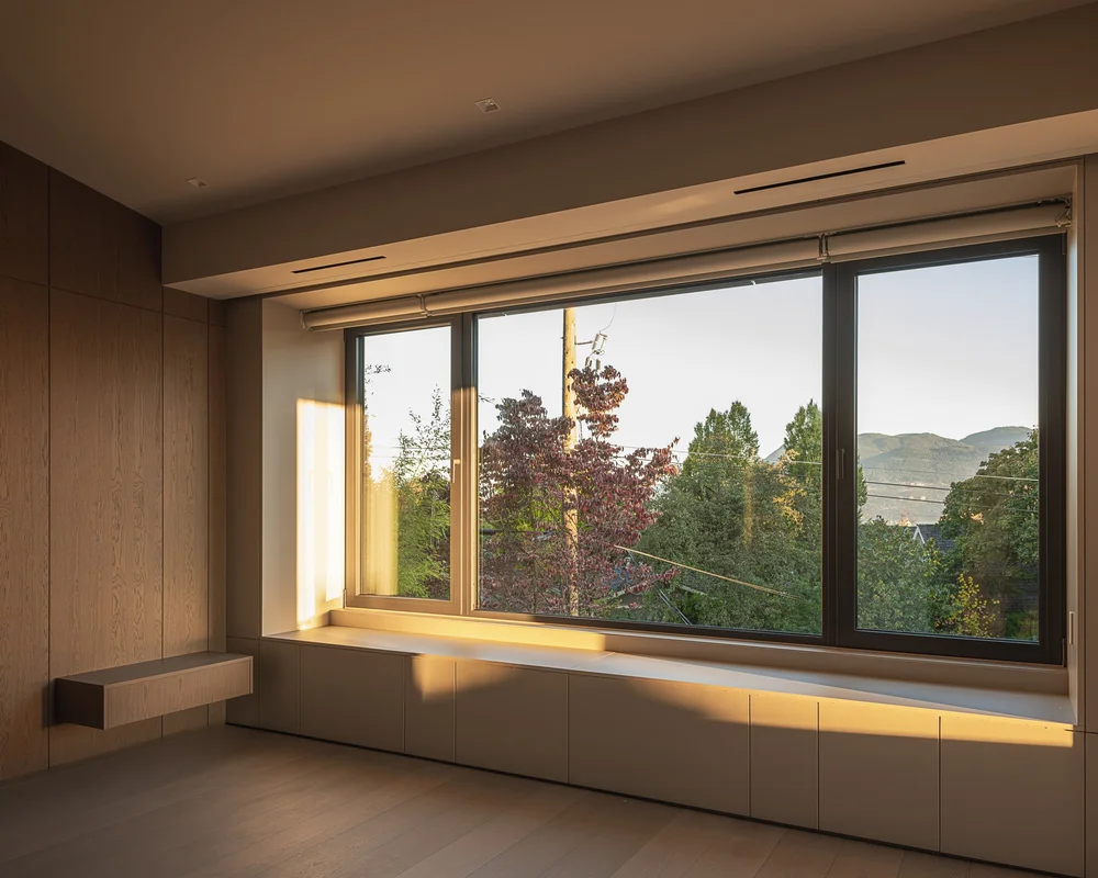 Built in bench below a wide window, low sun raking across the drawer fronts