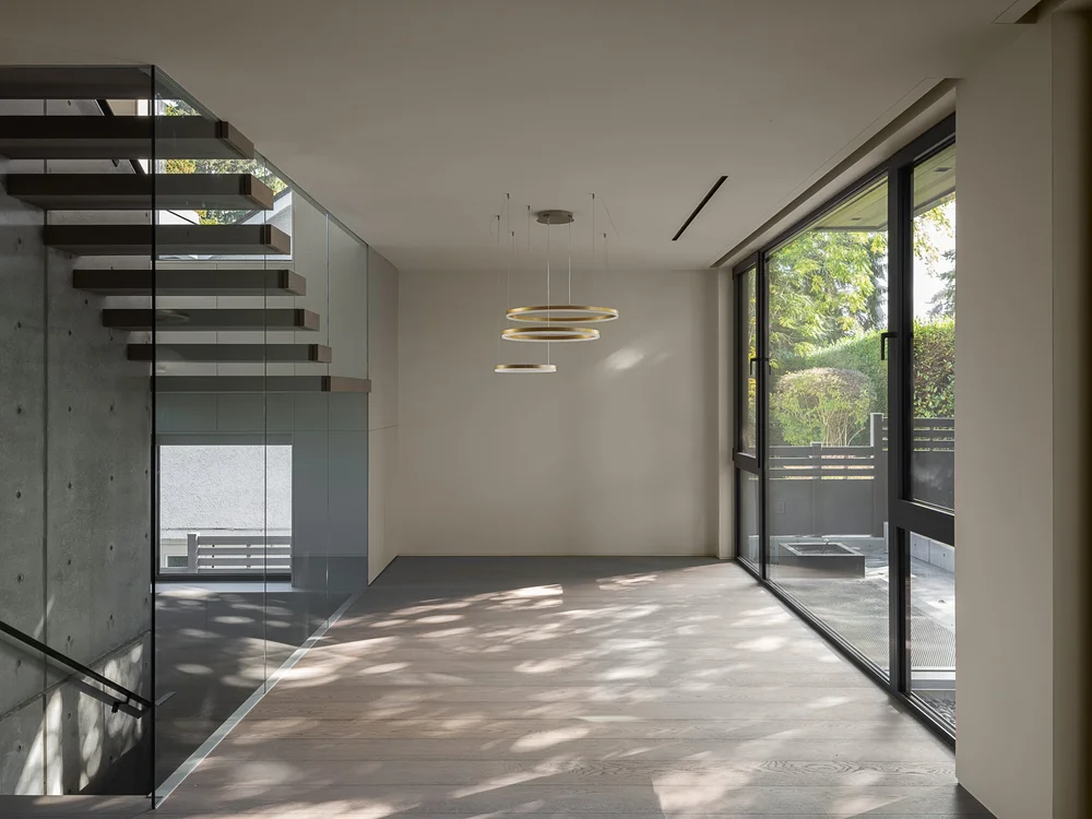 Empty room with ring pendants, sliding glass to the terrace and shadows on the floor
