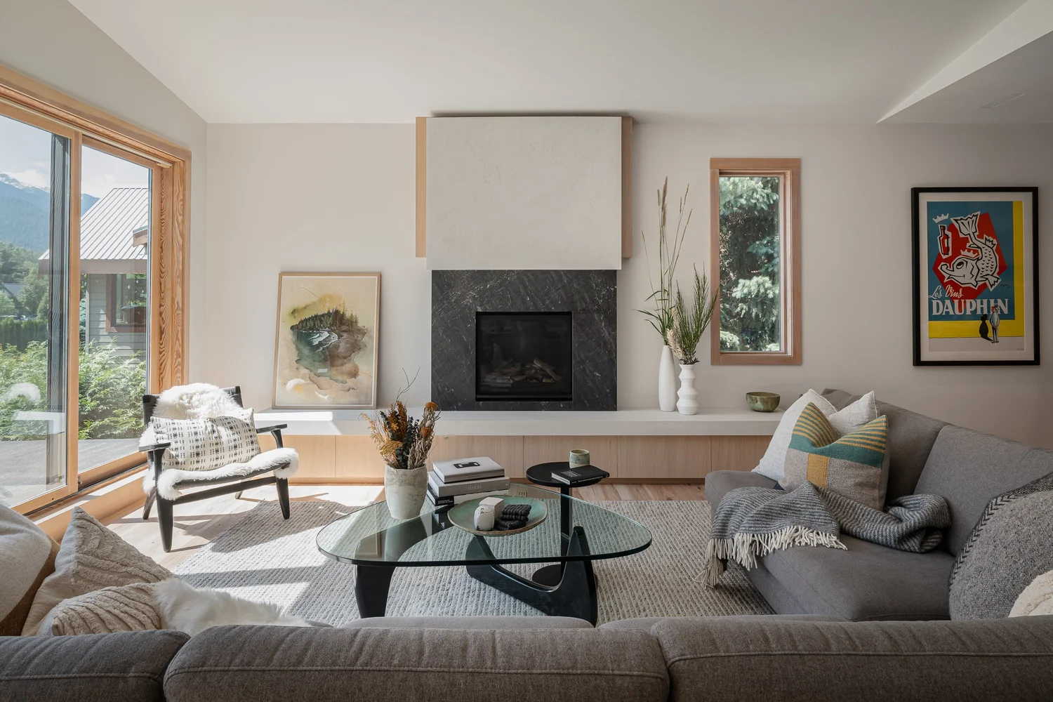 Living room with a sectional and glass table, sliding door to the deck and trees