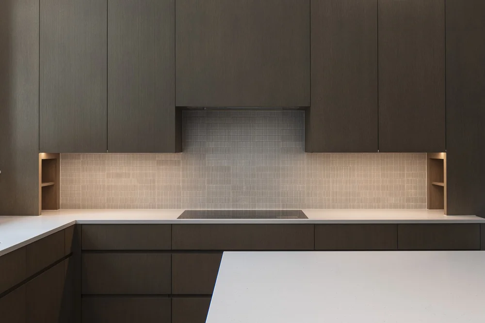 Kitchen elevation straight on, cooktop under a pale tile wall between two lit niches