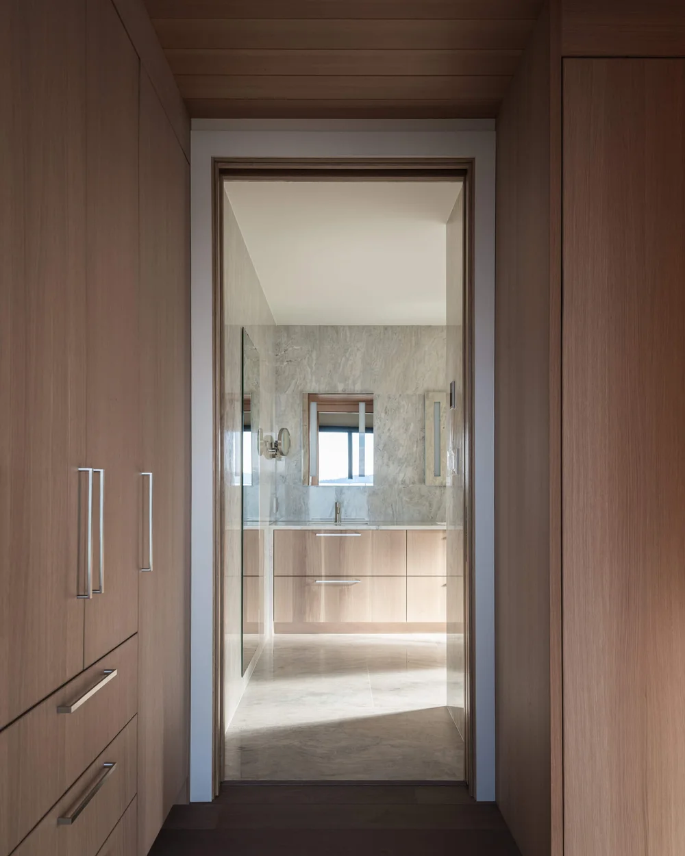 From a wood lined dressing room through an open door to the vanity in the ensuite