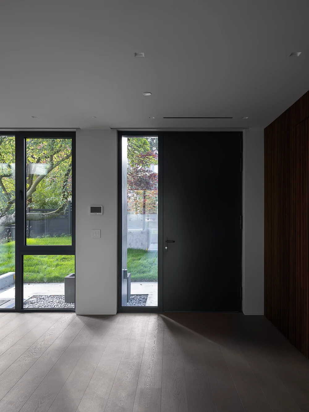 Entry hall from inside, dark door and glazed sidelight opening to the lawn