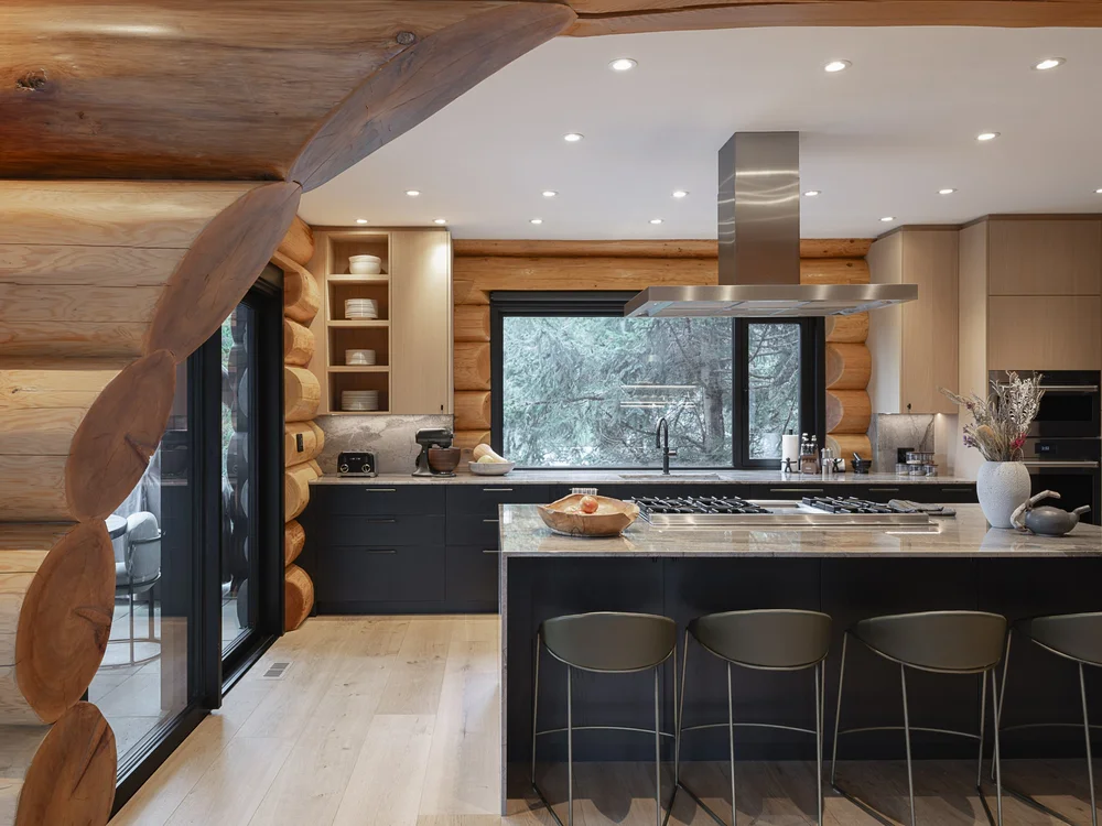 Kitchen island with four stools, a window over the range and open shelves of dishes