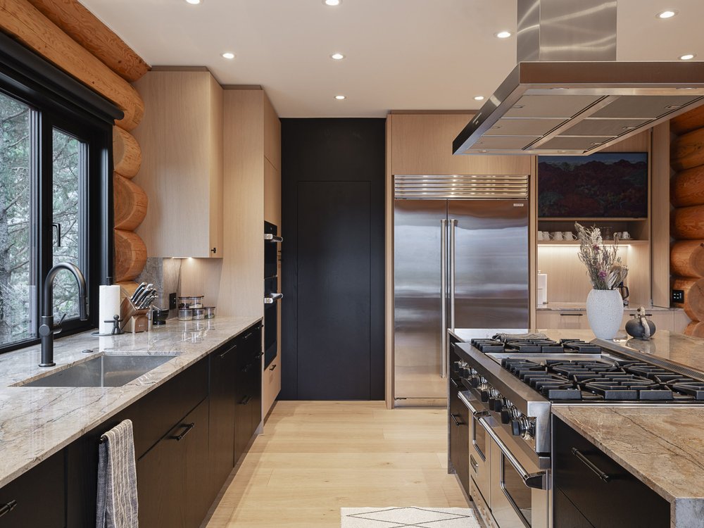 Along the kitchen run, sink under a window at left, range and hood at right