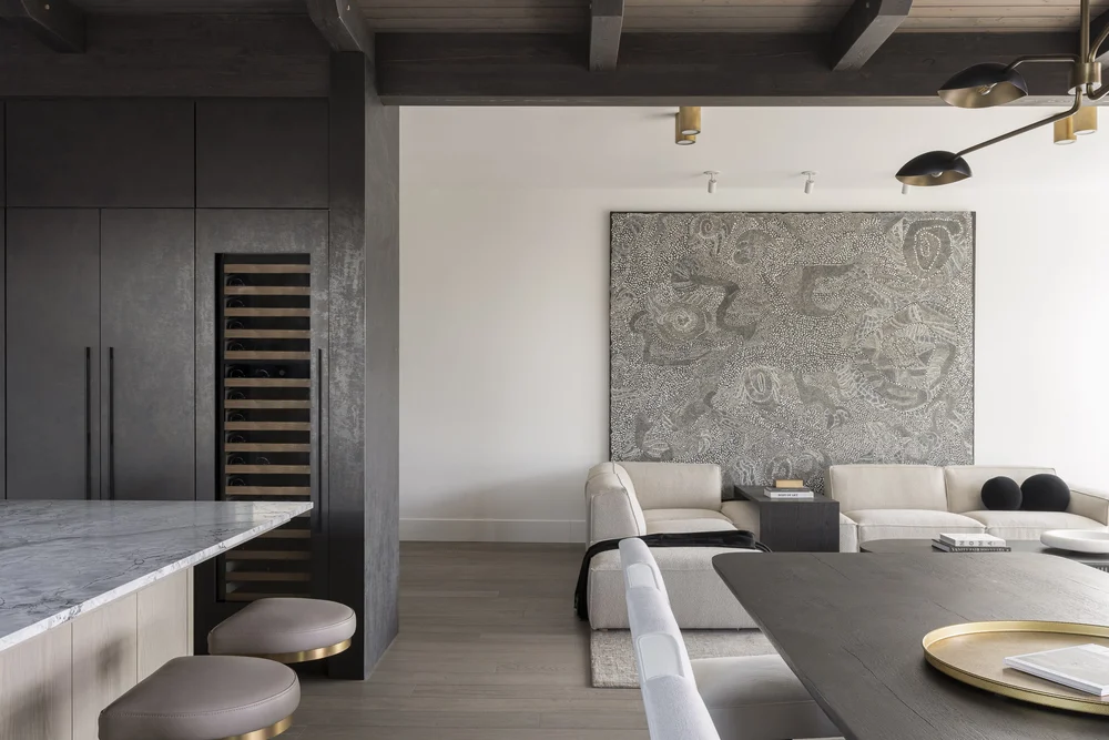 Dining table and sectional under a large textured artwork on a white wall