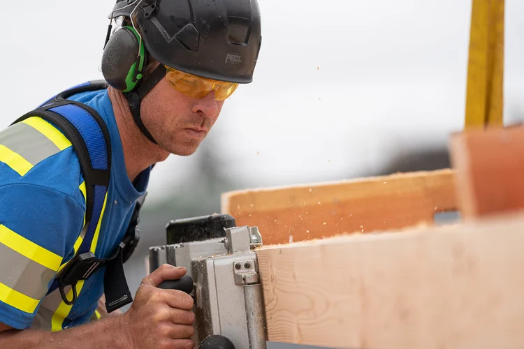Worker cutting mass timber with a saw