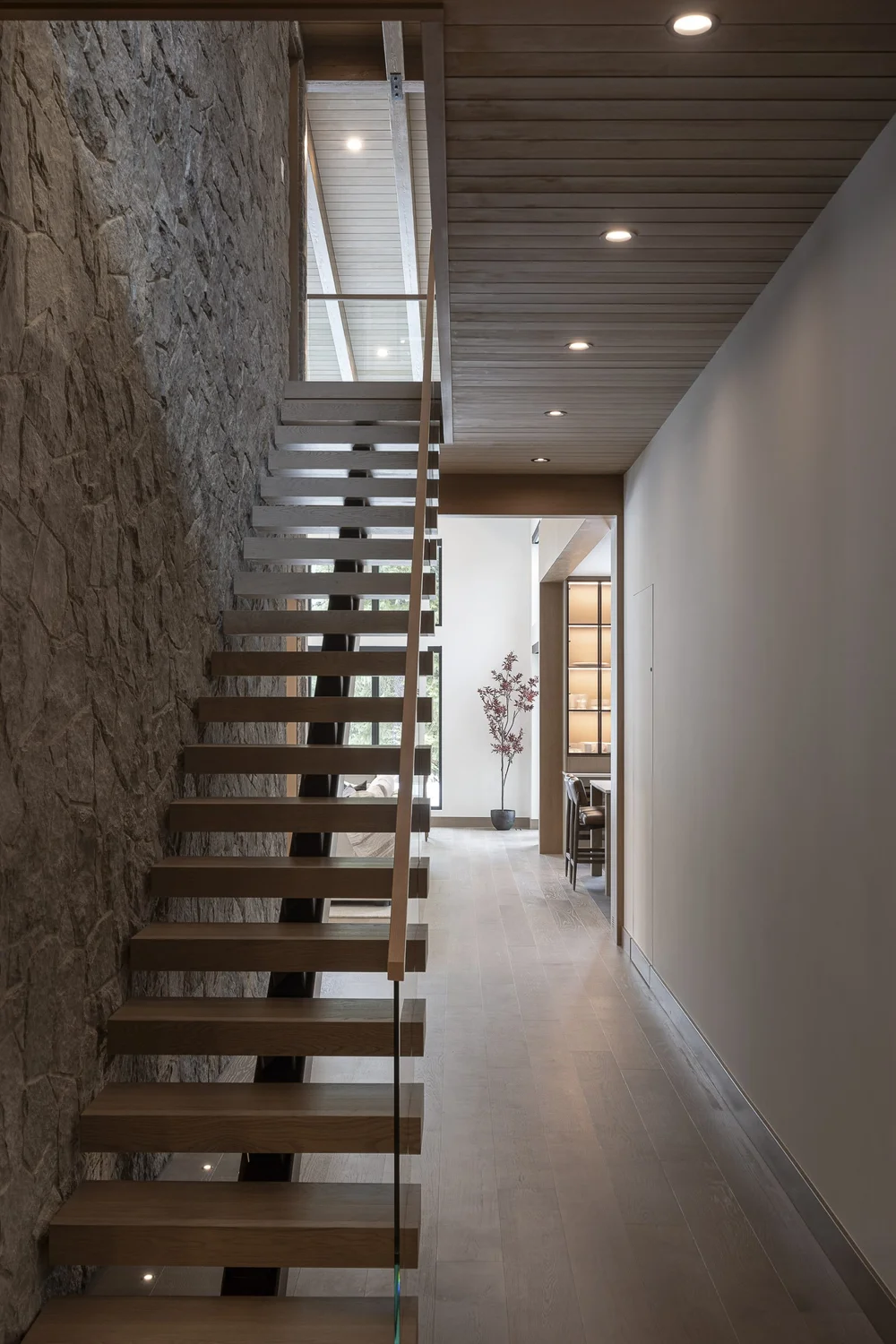 Looking along a corridor to the open stair, stone wall at left, planked ceiling above