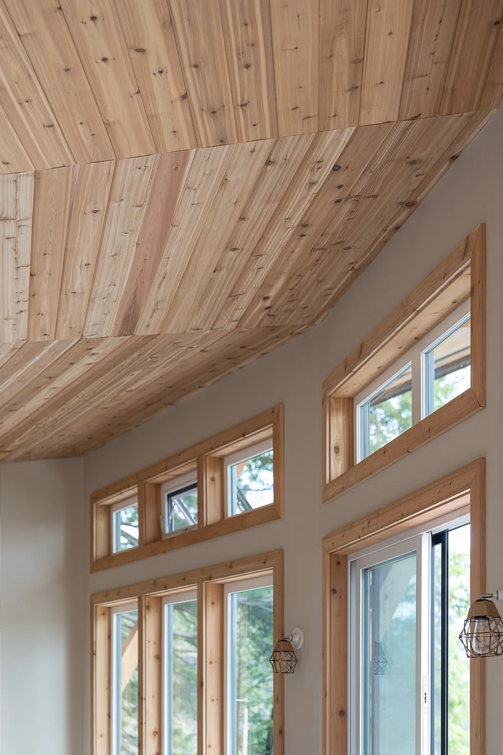 Wood boards running across the ceiling to a wall of tall windows in wood frames