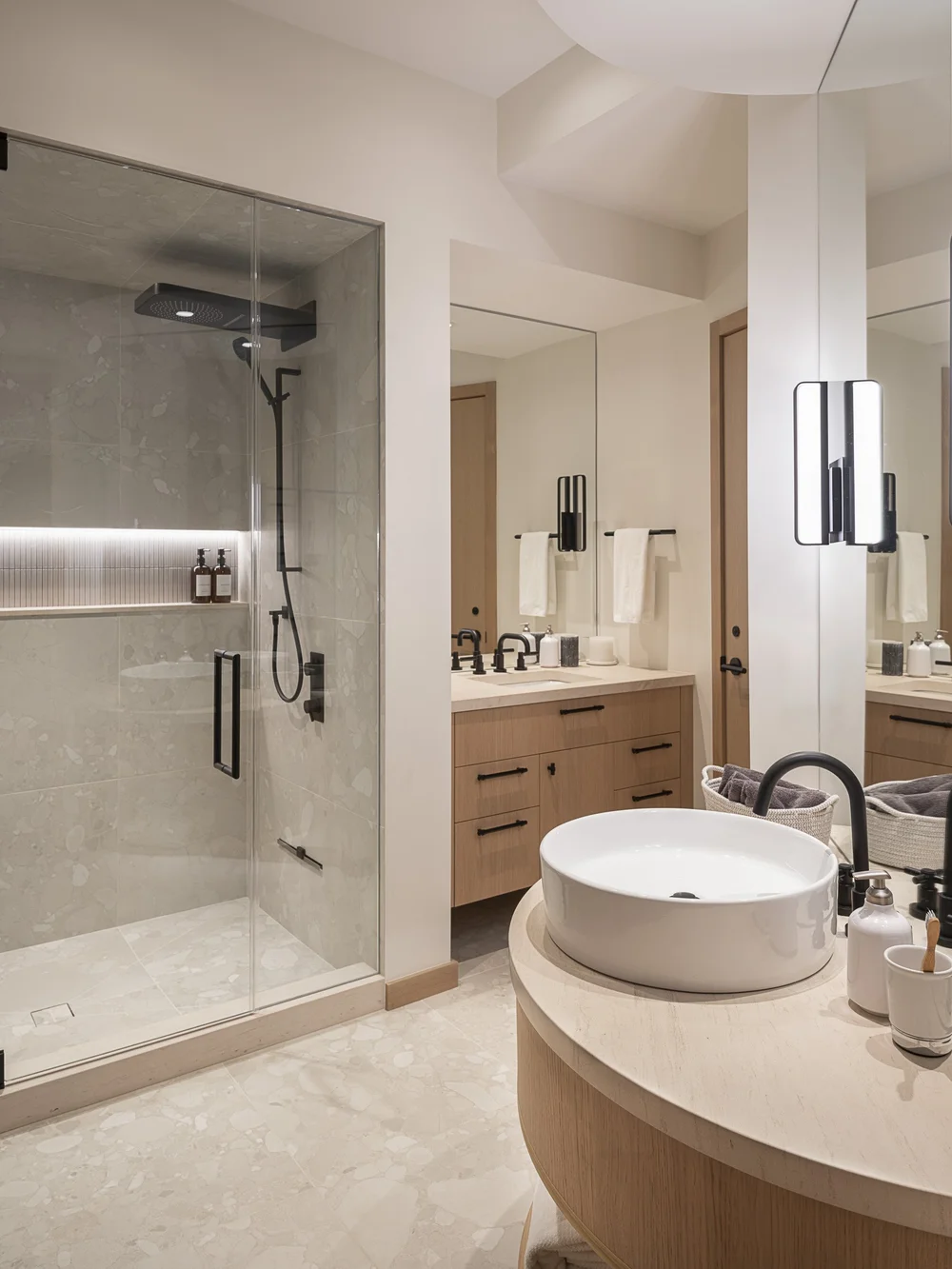 Round basin on a counter, the vanity and towel basket behind reflected in a mirror