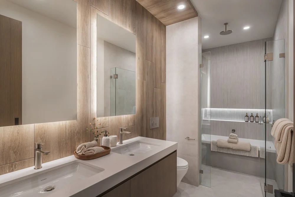 Bathroom with a backlit mirror over twin basins, shower and tub in the room beyond
