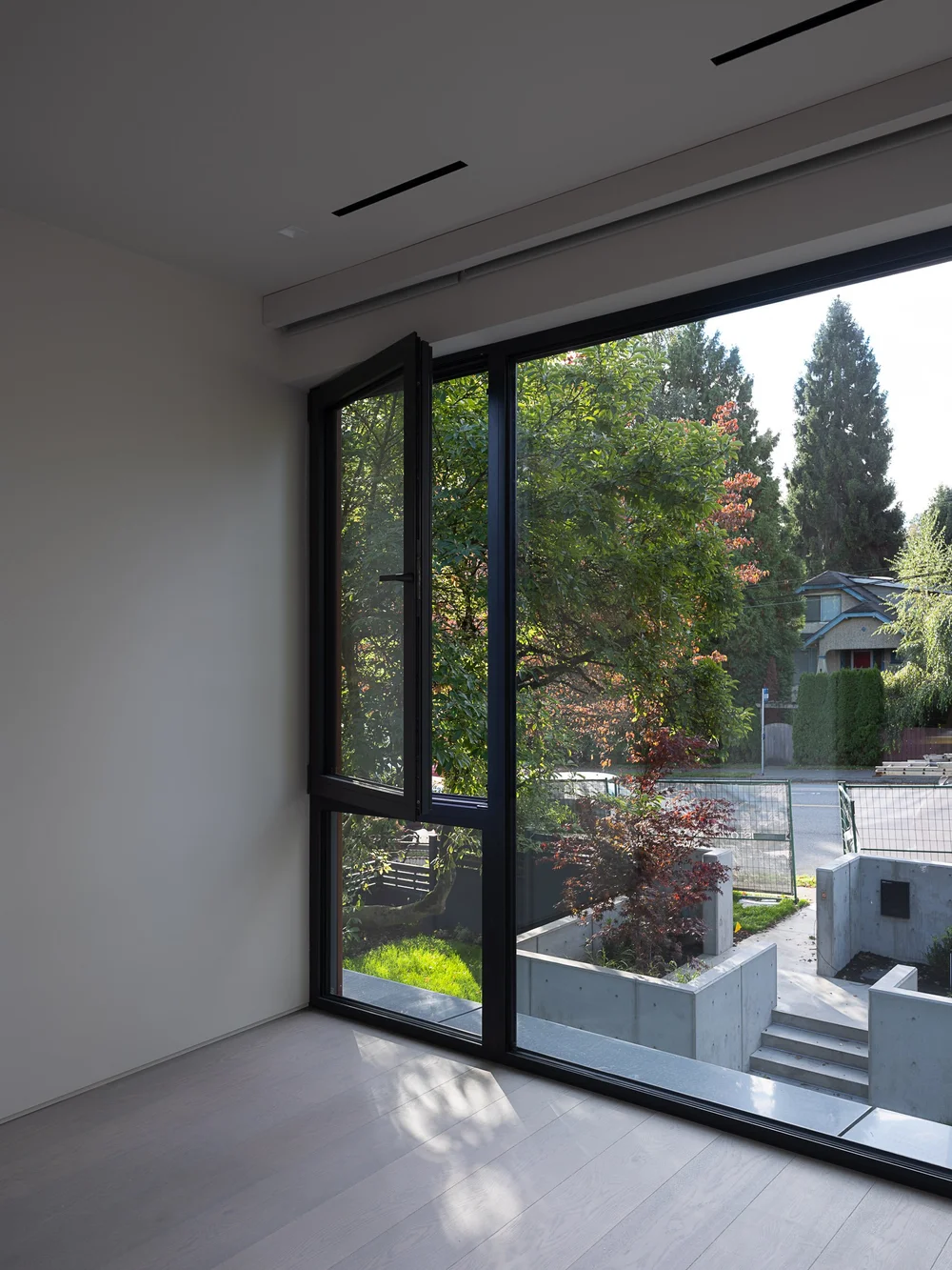 Corner window with dappled light, garden walls and a neighbouring roof beyond