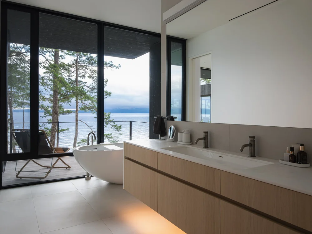 Twin taps on a long vanity under a wide mirror, glazing onto the water