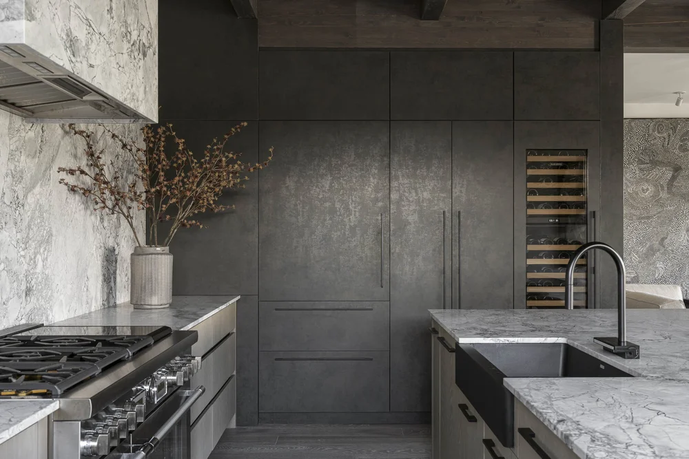 Range under a hood with tall dark cabinets and a glass fronted wine cabinet