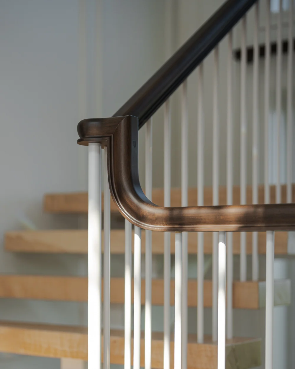 The dark handrail turning above slim pale spindles, open treads carrying on behind