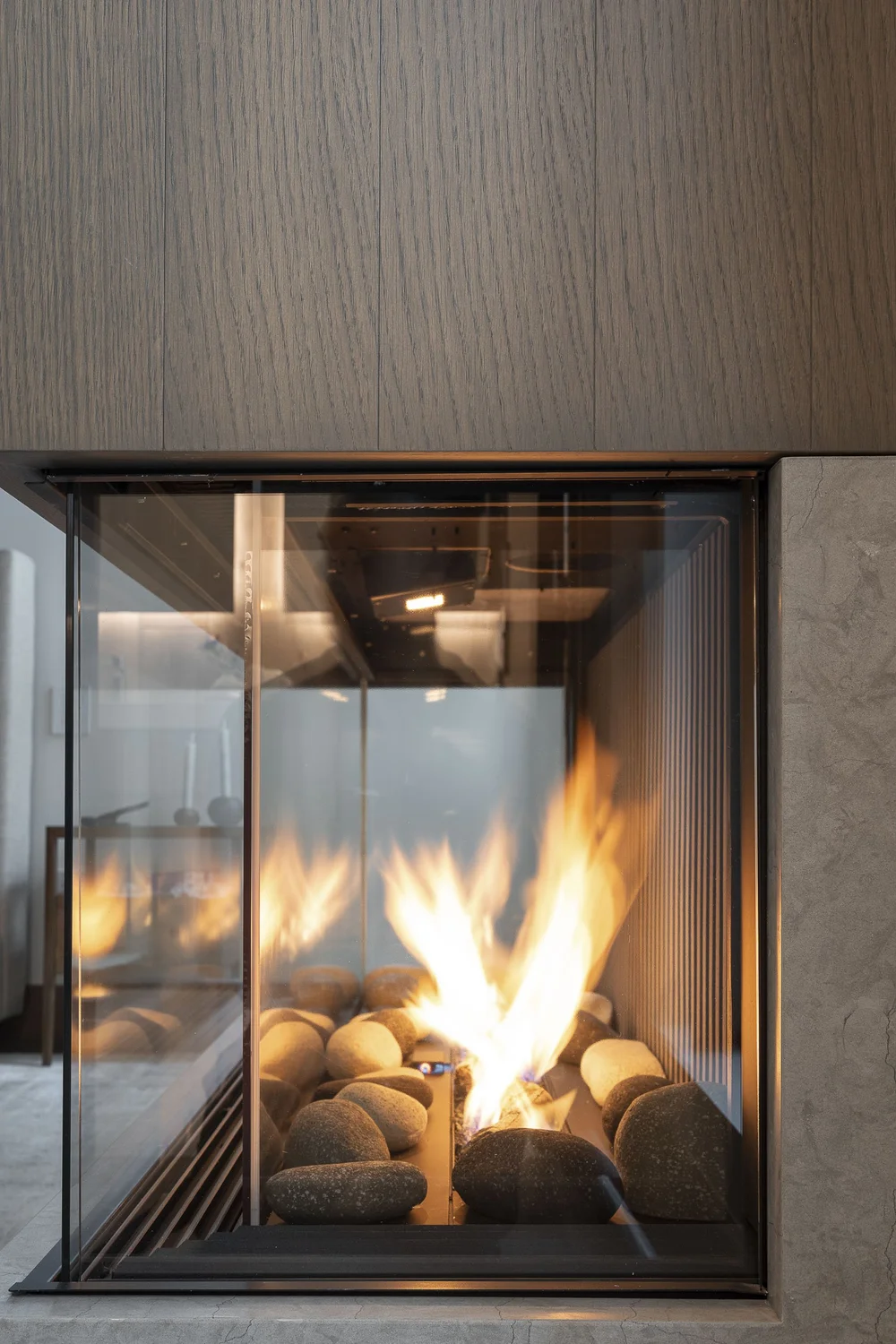 A long fire burning over pale stones behind glass, ribbed glass panel beyond