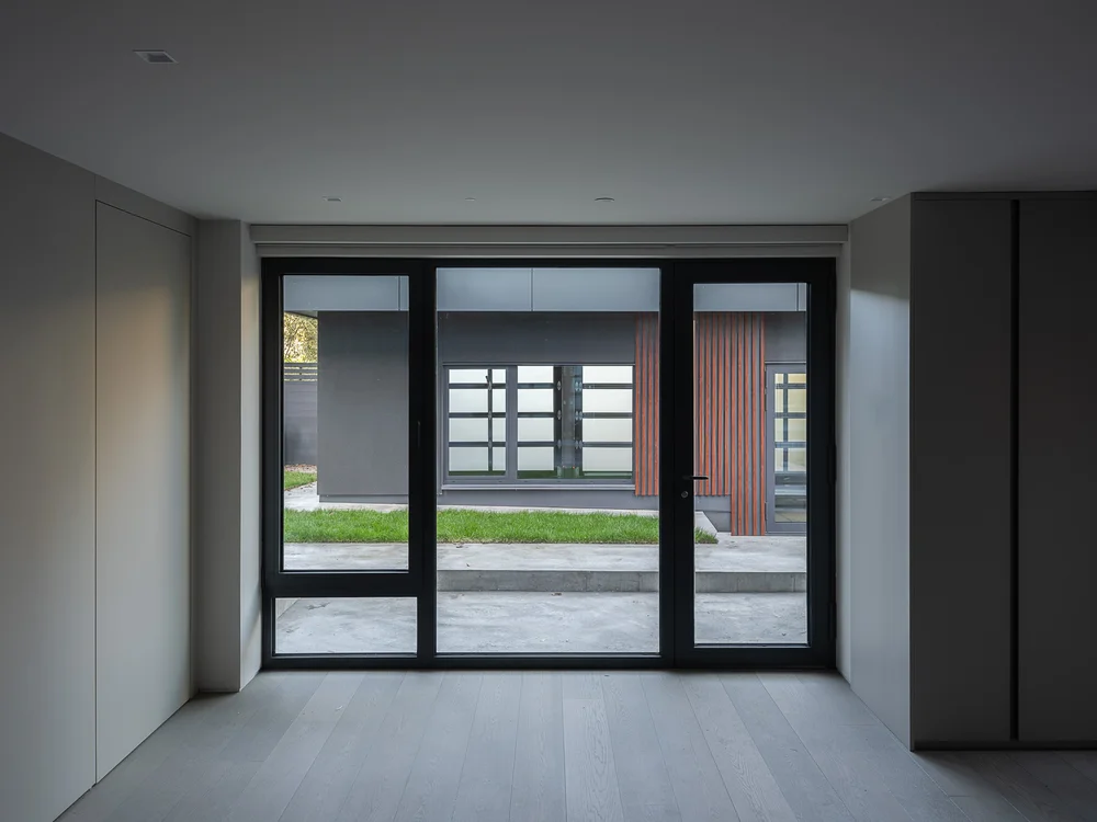 Glazed door onto the concrete patio, lawn and the outbuilding with its slatted panel