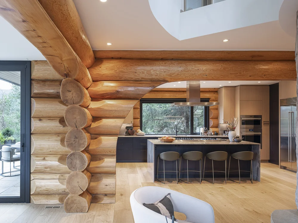 Log beam framing the kitchen, a bright opening in the ceiling above the island