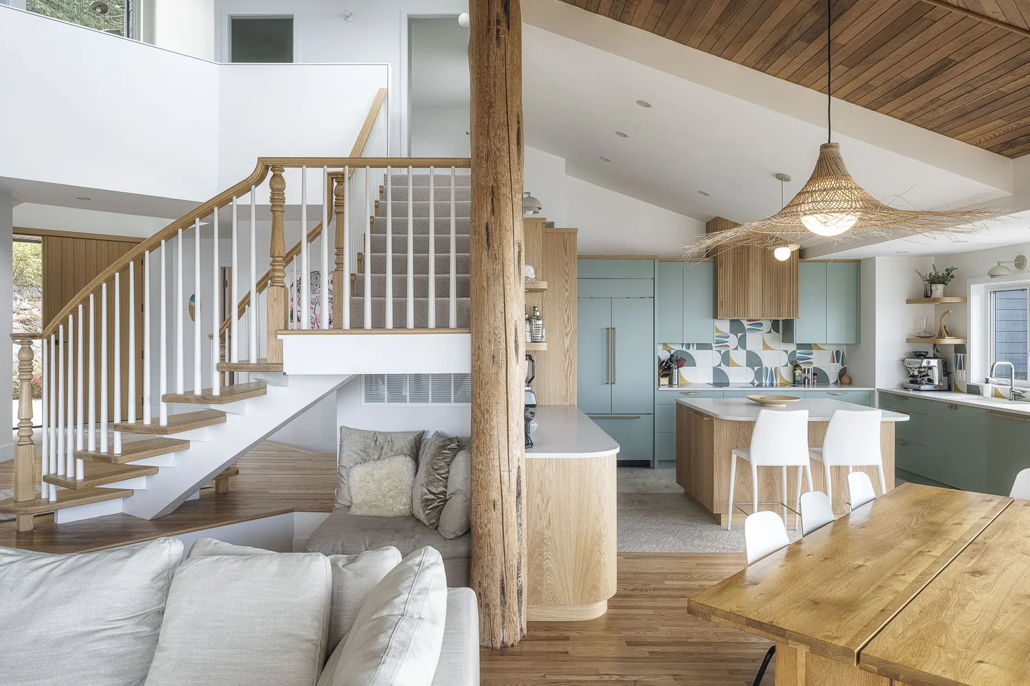 Stair with turned spindles beside a rough timber post, the kitchen and dining beyond
