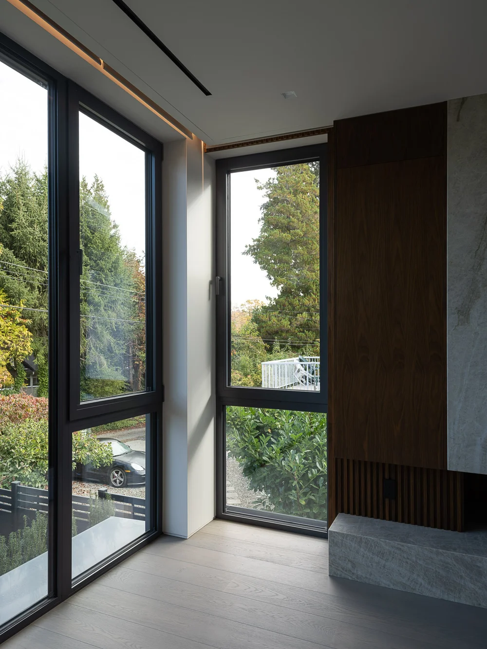 Corner glazing meeting at a mullion beside timber panelling and a stone hearth