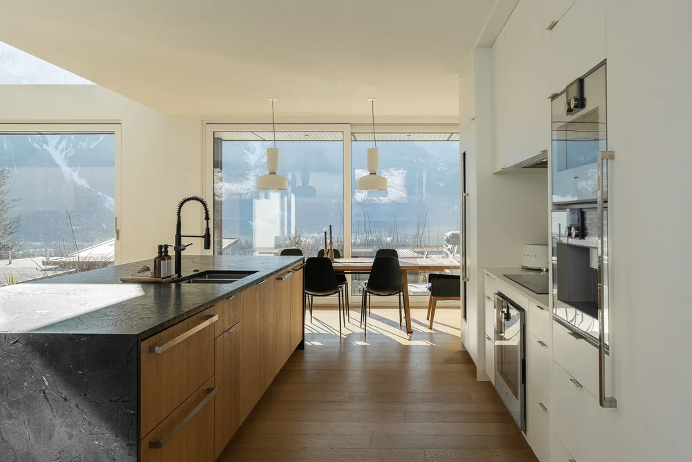 Along the length of the island to a dining table and glazing onto the mountain