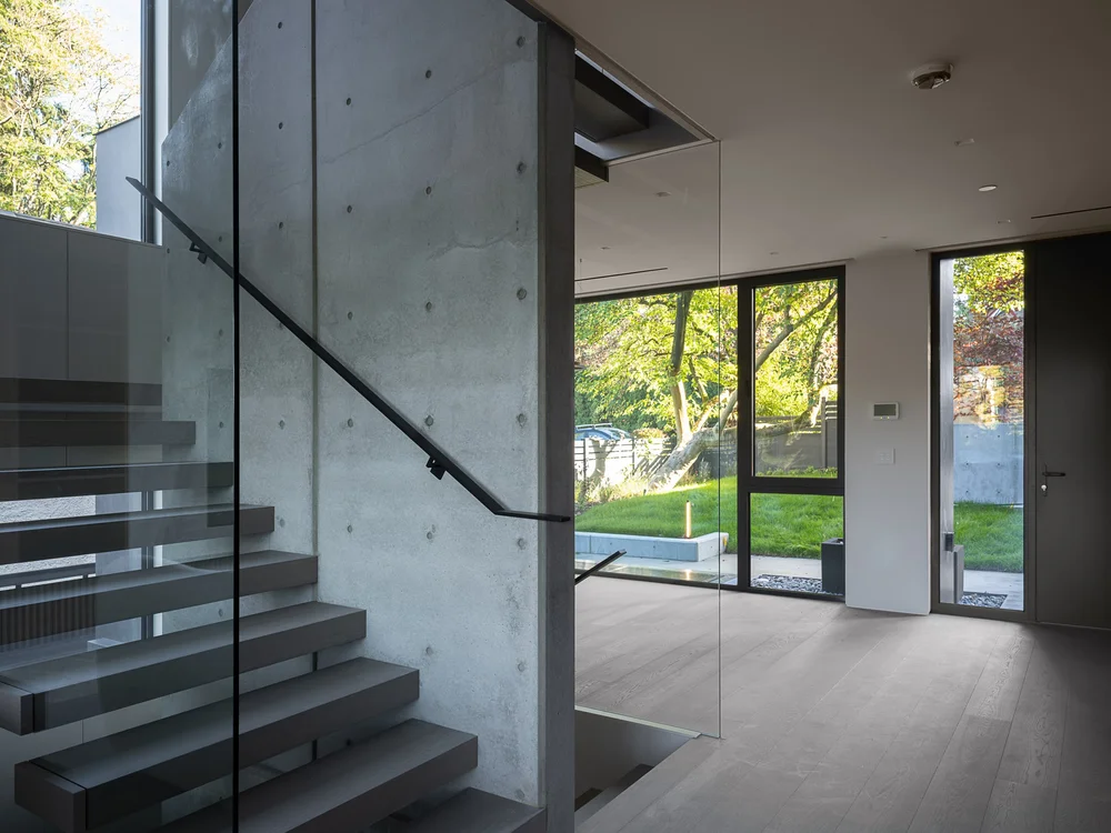 Stair and handrail against the concrete wall, glazing to the lawn and a side door